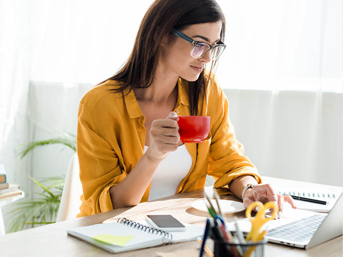 beautiful freelancer working on laptop with coffee cup in home office
