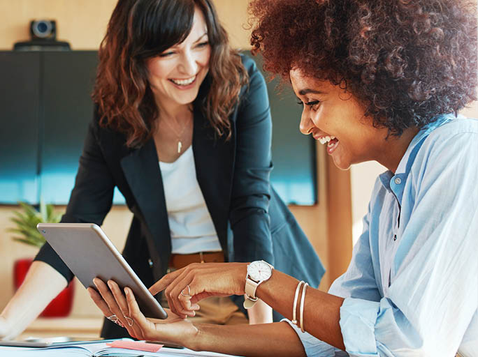 Shot of two businesswoman working together on digital tablet  Creative female executives meeting in an office using tablet pc and smiling 