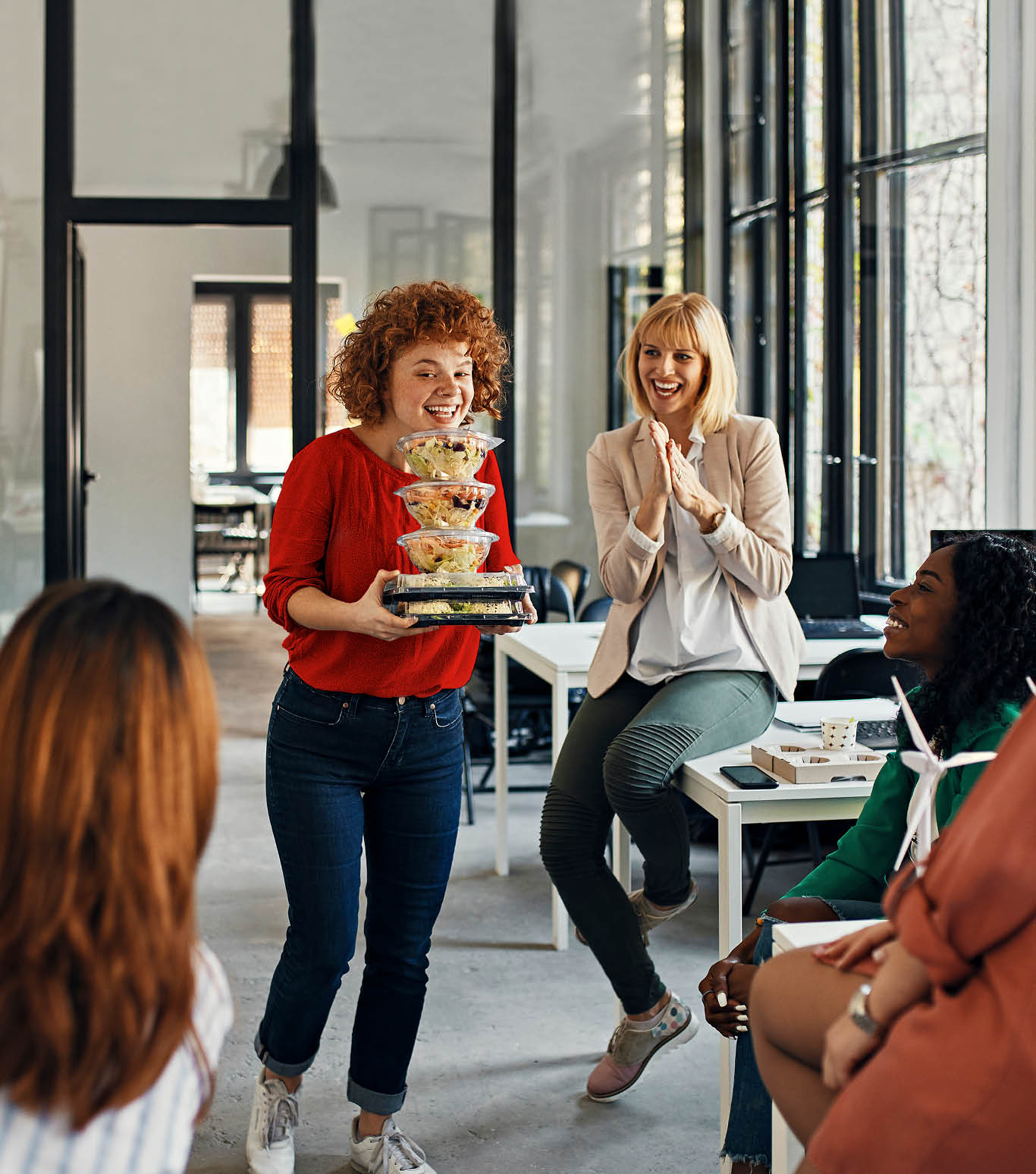 Happy businesswoman serving takeaway food to colleagues in office