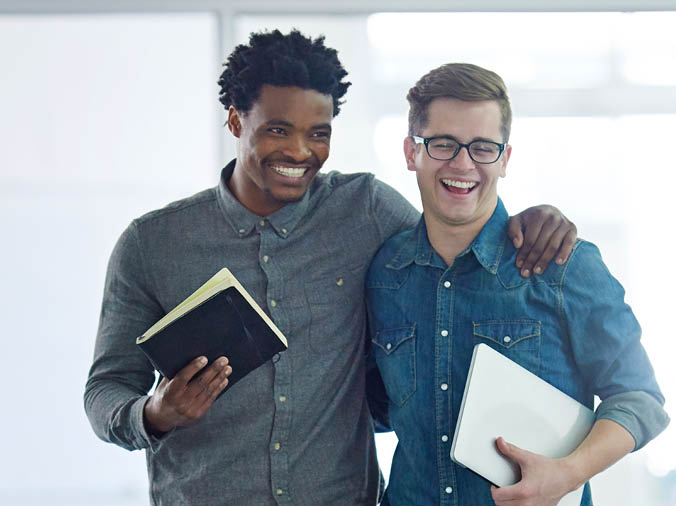 Shot of a two young coworkers talking together while walking arm in arm through their office